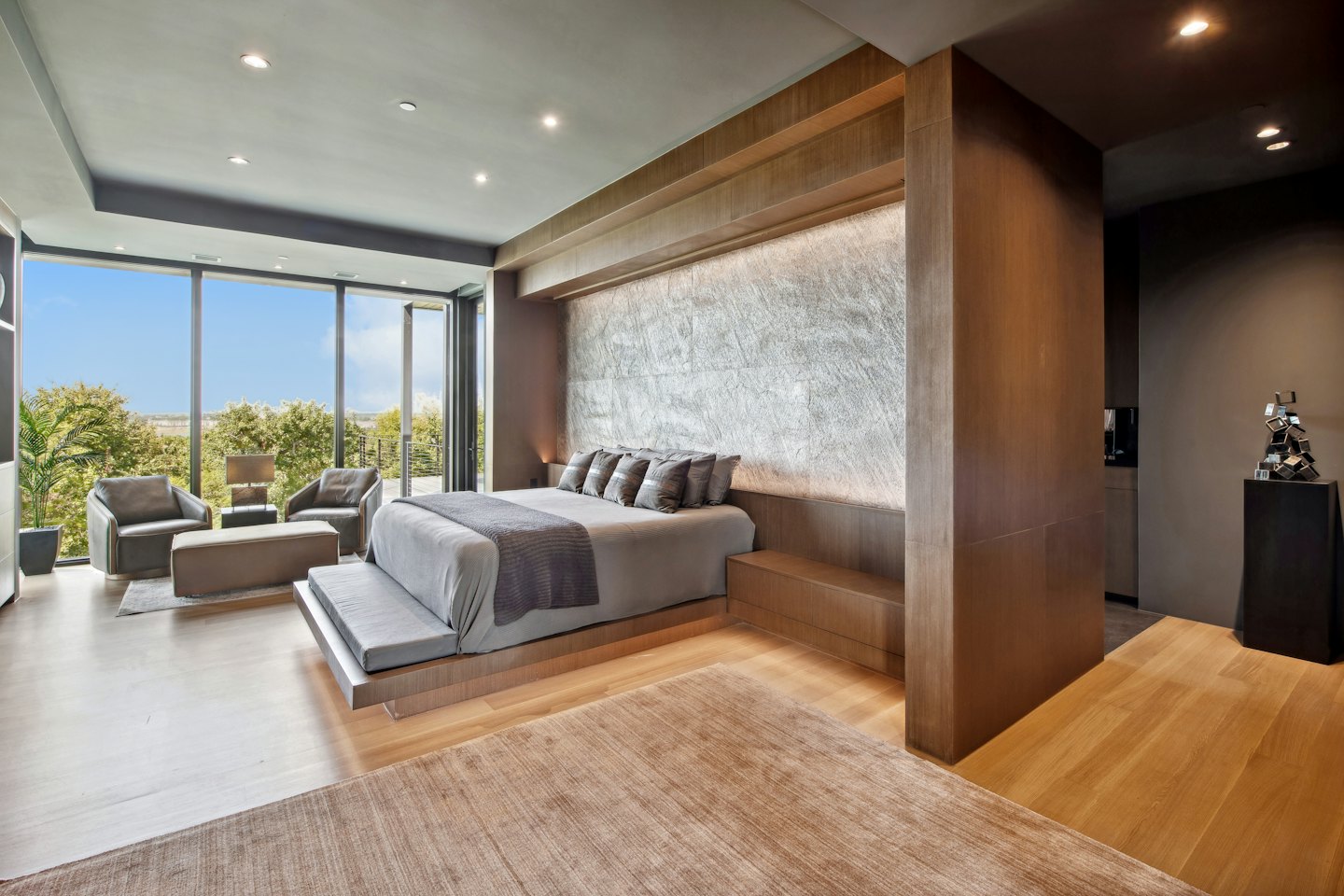 Modernes Schlafzimmer mit großem Bett und Blick auf eine üppige Landschaft.