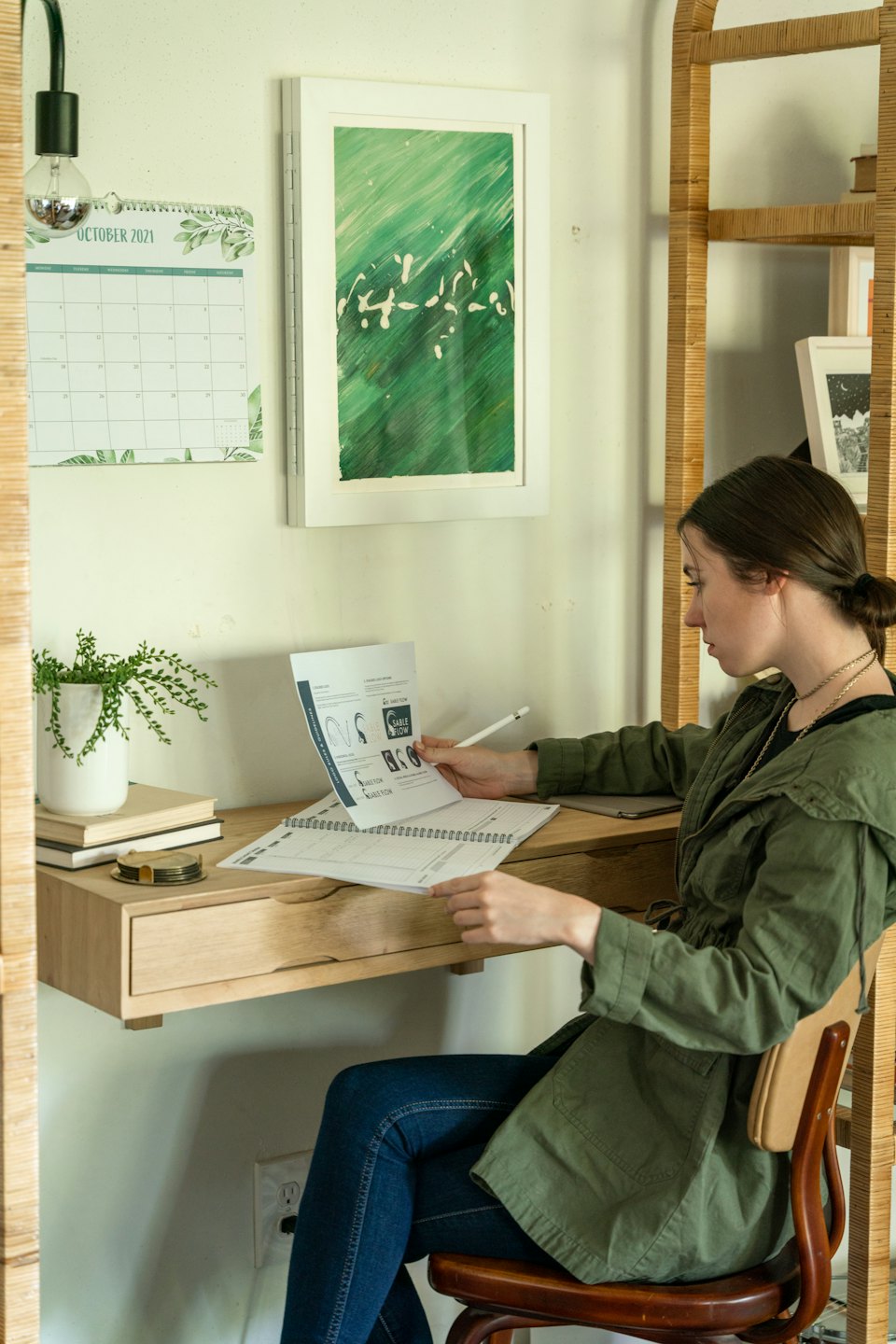 Frau prüft Dokument am Schreibtisch mit Stift im Heimbüro.