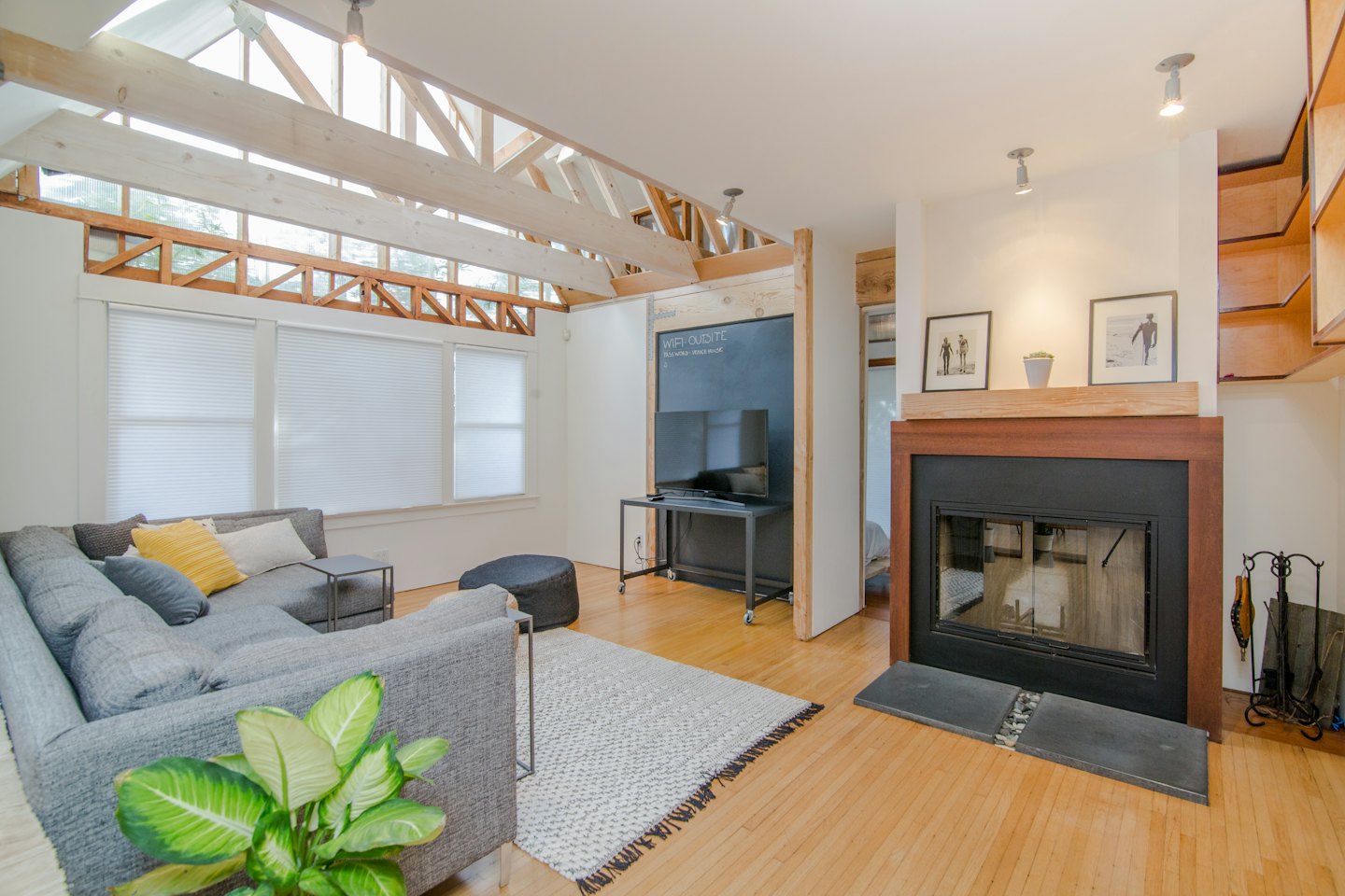 Modernes Wohnzimmer mit freiliegender Holzbalkendecke und grauem Sofa.