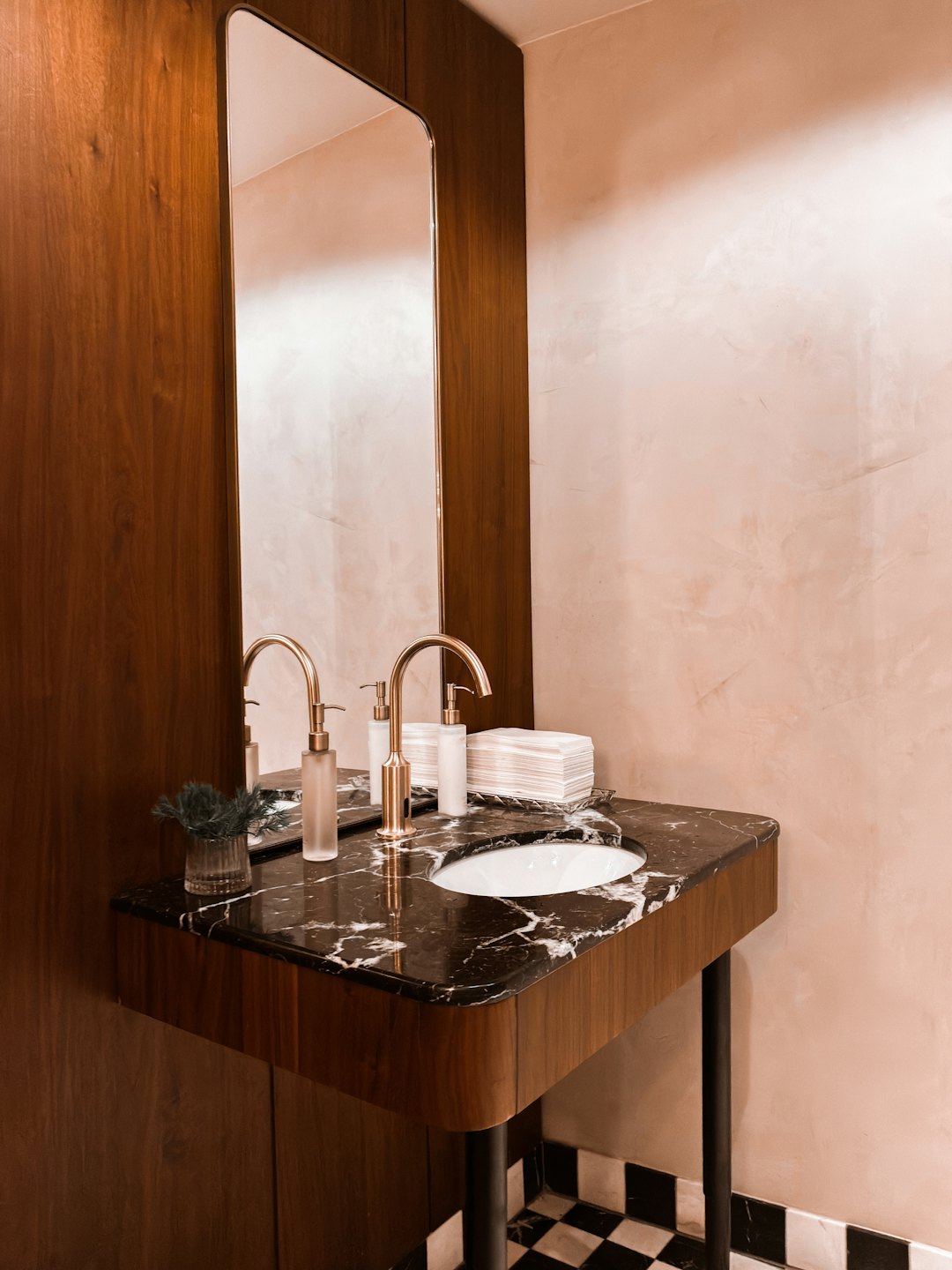 Waschtisch im Badezimmer mit schwarzer Marmorplatte und goldenen Armaturen.