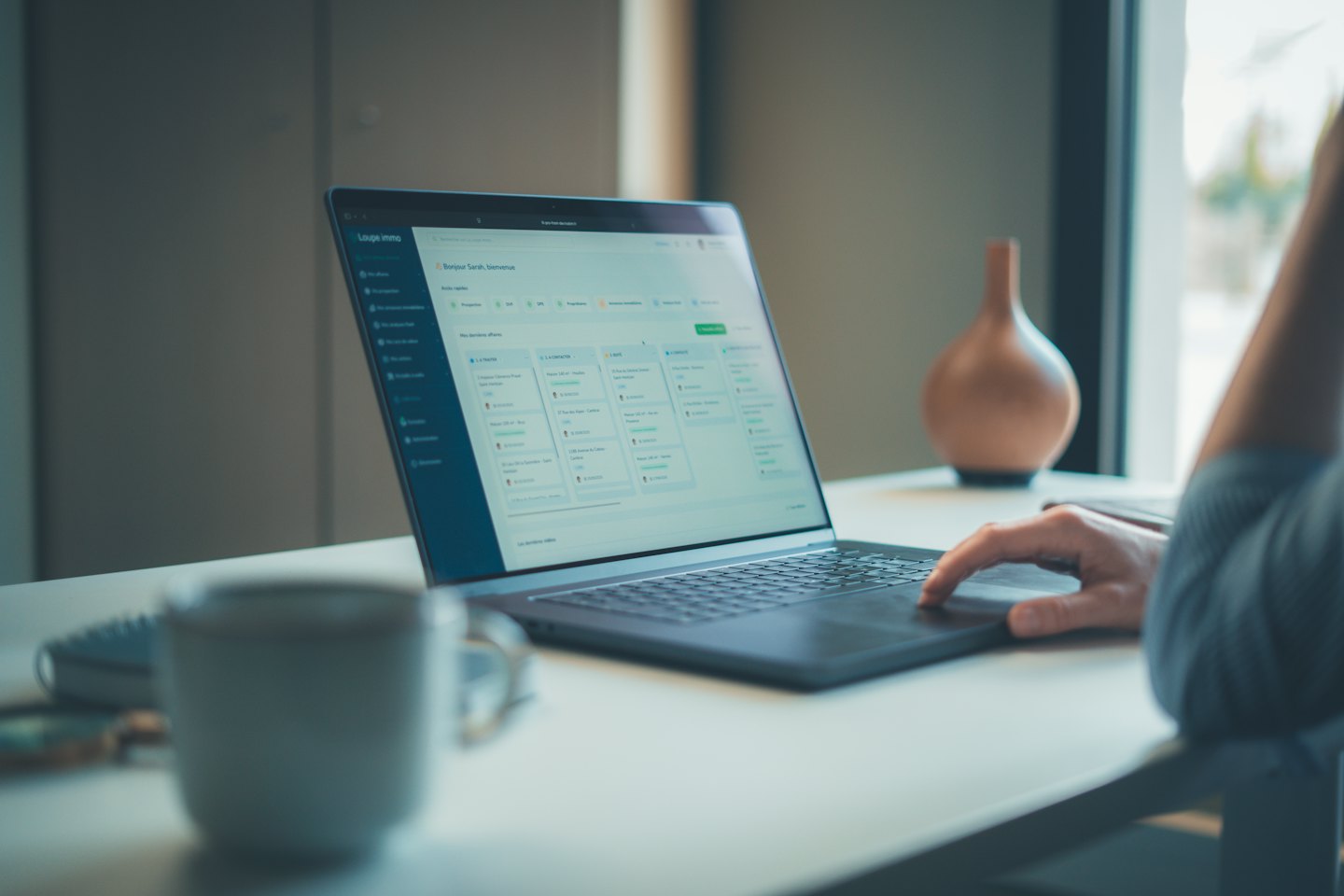 Hand benutzt Immobiliensoftware auf einem Laptop.